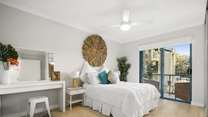 A bedroom with a bed, a desk, a chair, a mirror, a ceiling fan, and a balcony with a view of trees. - Family & Pet Friendly- Long Stays Welcome! (Bilinga)