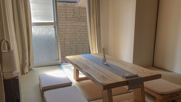 A tatami mat room with a wooden table, benches, and a remote control on the table. - ZAITO Tokyo Waseda Economy Inn (Tokyo)