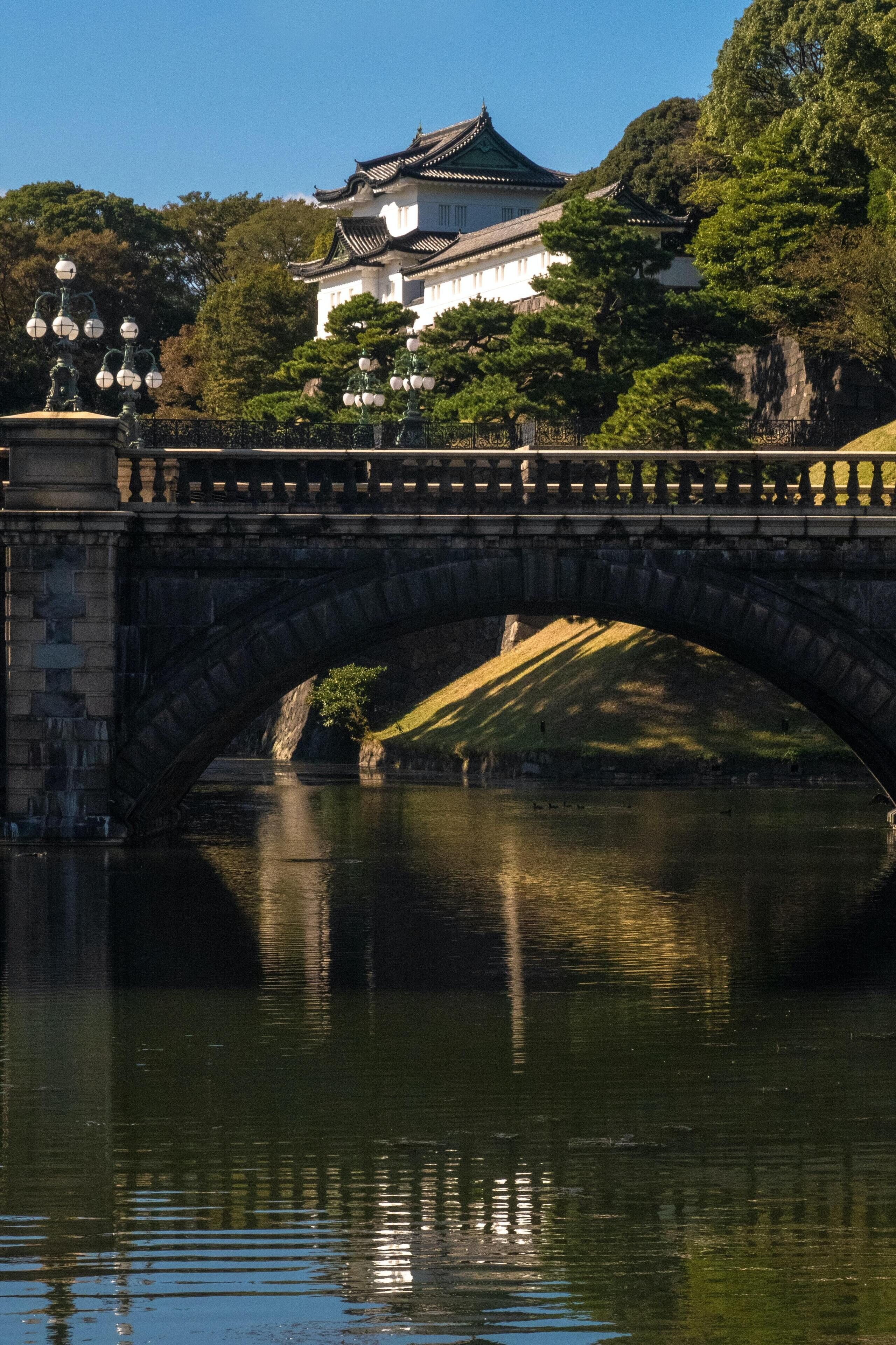 Un ponte di pietra sopra un fiume, con un edificio tradizionale sullo sfondo.