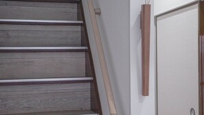 A staircase with wooden steps and a handrail, leading to a door with a panel. - ZAITO Tokyo Waseda Economy Inn (Tokyo)