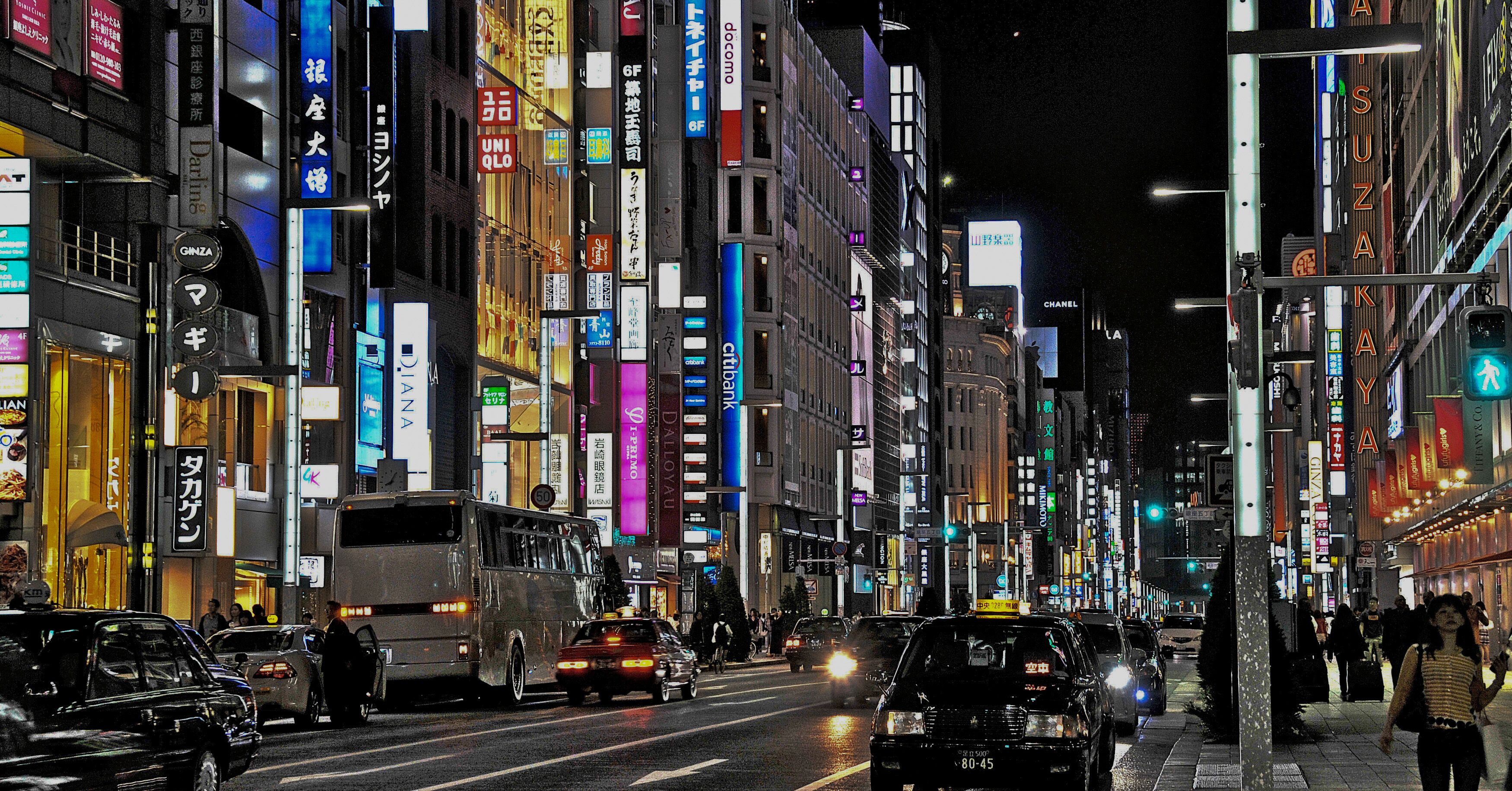 A busy urban street at night with illuminated signs and vehicles.