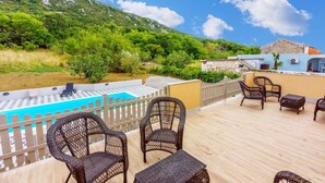 A poolside area with wicker furniture and a view of a mountain.