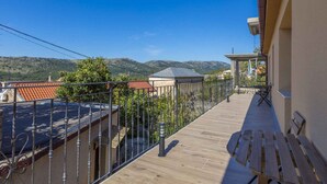 A balcony with a view of mountains, a wooden deck, and a metal railing.
