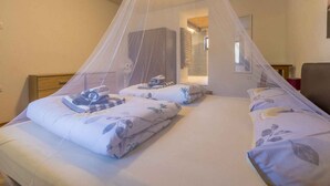 A bedroom with two beds, a canopy, a wooden headboard, a nightstand, and a mirror on the wall.