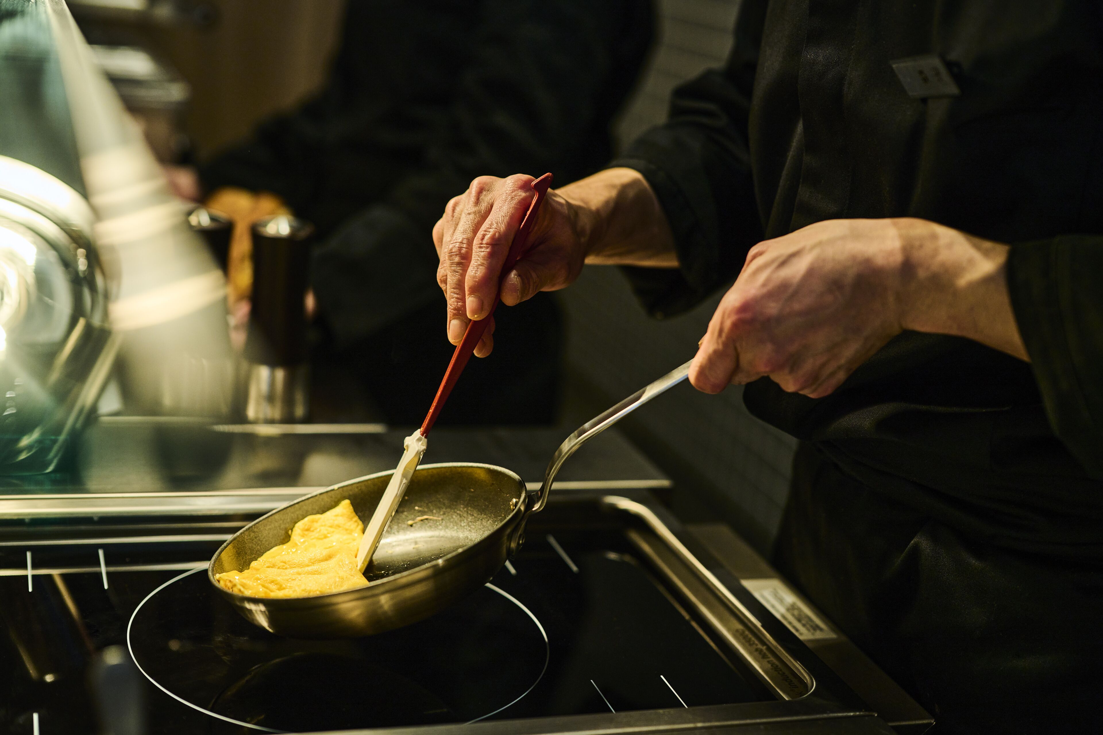 A person cooking an omelette on a stove.