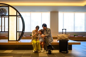 A seating area with a bench, a suitcase, and a decorative wall piece.