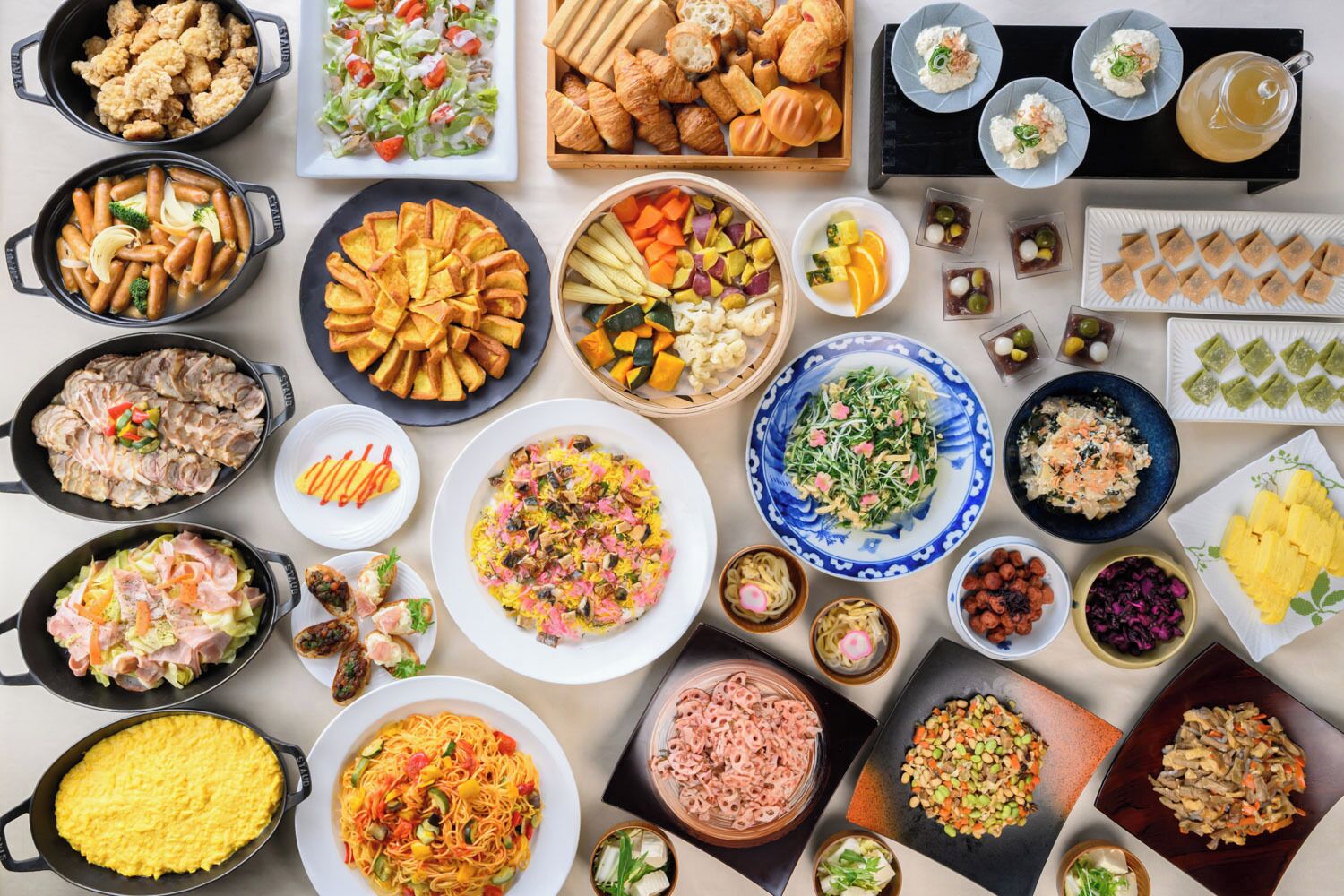 A variety of dishes arranged on a table, including salads, meats, and pastries.