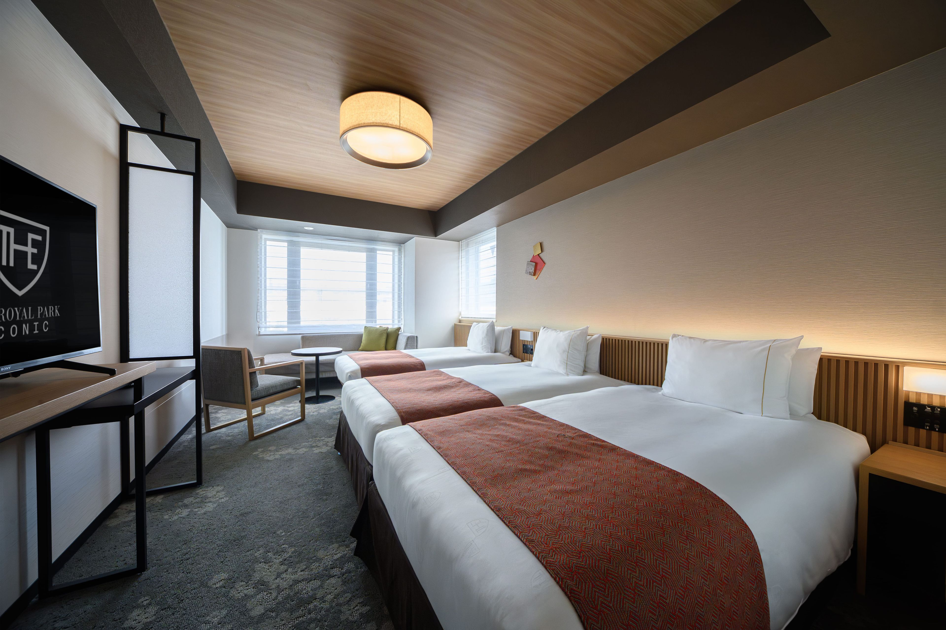A hotel room with a large bed, a desk, a chair, and a television.
