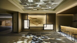 A modern hotel lobby with a geometric ceiling design, a central art installation, and a reception area with bar stools. - The Royal Park Hotel Kyoto Umekoji (Kyoto)