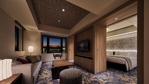 A modern hotel room with a sofa, ottoman, and a bed with a headboard. - The Royal Park Hotel Kyoto Umekoji (Kyoto)