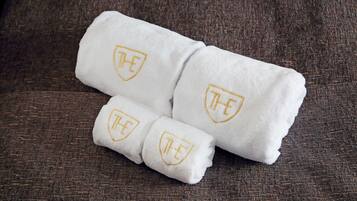 A set of white towels with a gold emblem on a textured brown surface.
