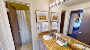 Bathroom features dual sinks, a shower, and a vanity with a mirror.