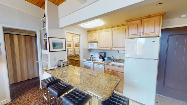 Modern kitchen with a central island, equipped with a microwave, coffee maker, and refrigerator.