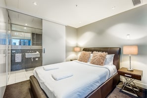 Relax in a spacious room with a large bed, city views, and a glass shower area.