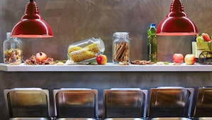 Una disposición tipo bufé con pasta, frutas y especias en estantes, y varios recipientes de comida debajo.