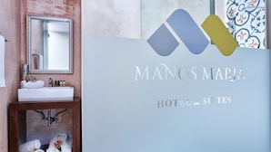 Mostrador de recepción de hotel con un espejo, un lavamanos y una presentación de toallas y artículos de aseo.