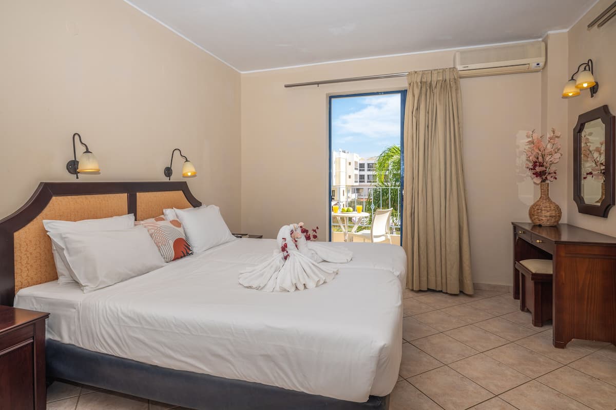 Habitación de hotel con una cama grande, un escritorio, una silla y vistas al exterior.