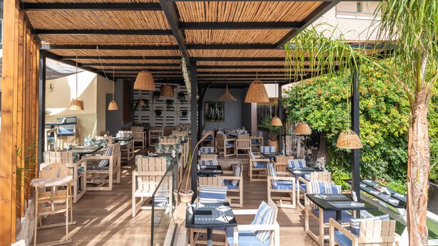 Un espacio al aire libre con mobiliario de madera y lámparas de mimbre colgantes.