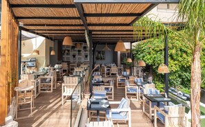 Uma área externa com assentos de madeira e luminárias de vime suspensas.