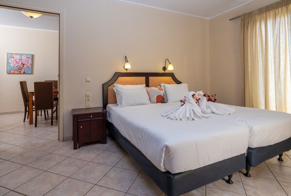 Uma cama de casal com lençóis brancos, duas luminárias fixadas na parede e uma mesa de cabeceira.