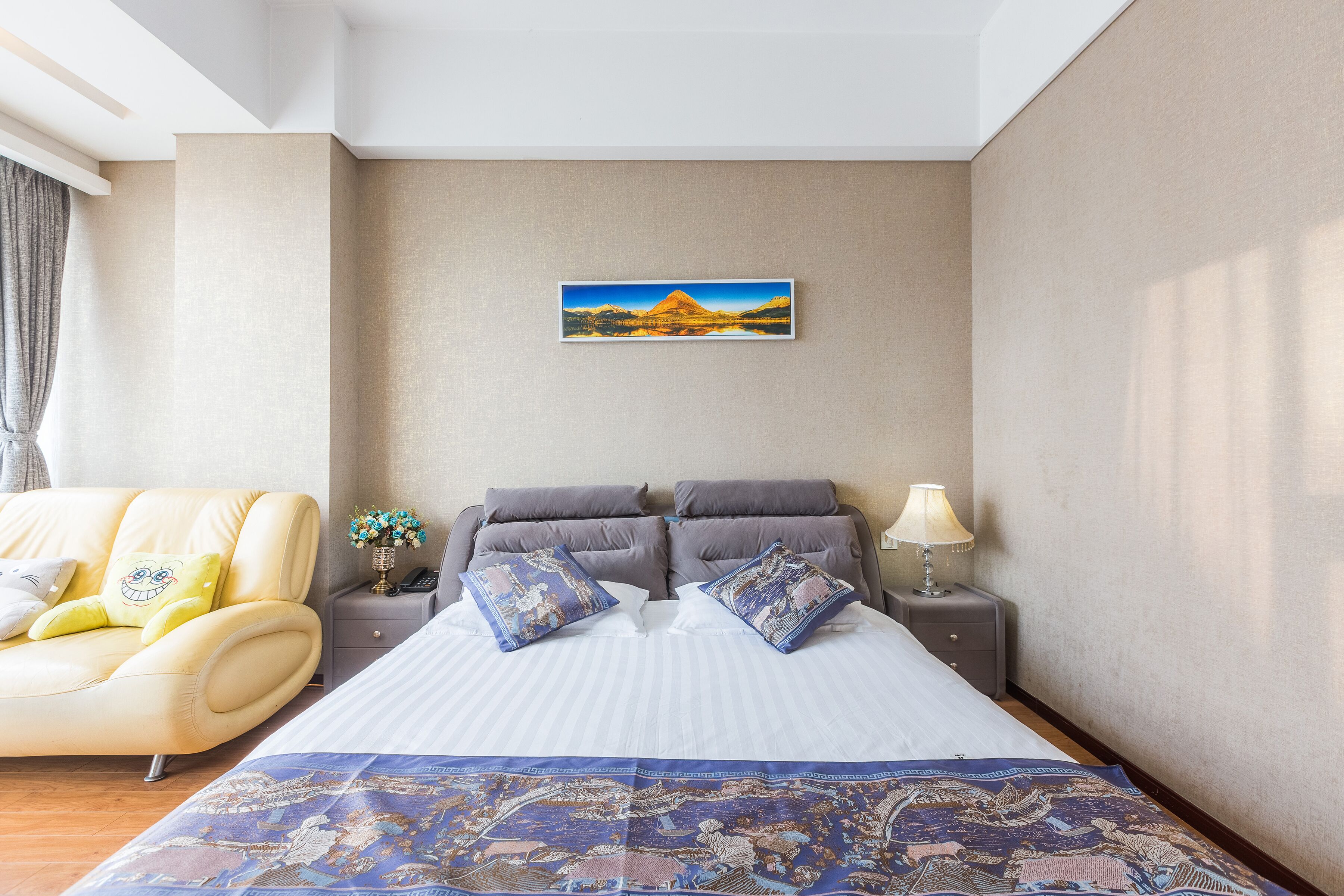 Une chambre d’hôtel avec un grand lit, un canapé, une table de chevet avec une lampe et un tableau au mur.