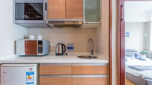 Una cocina compacta con microondas, hervidor y refrigerador.