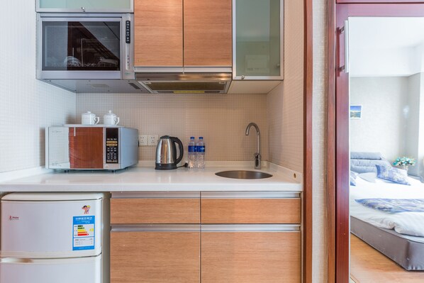 Una cocina compacta con microondas, hervidor y refrigerador.