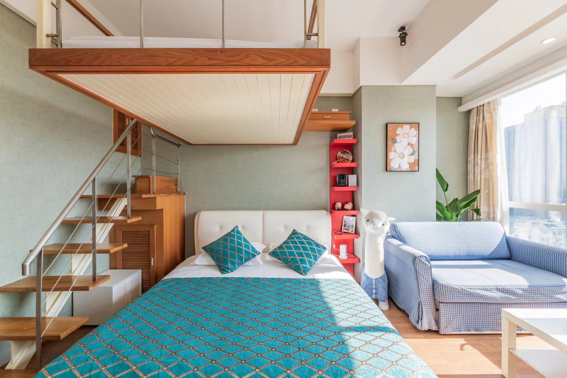 Une chambre moderne avec un lit en mezzanine, un canapé, une étagère rouge et une grande fenêtre.