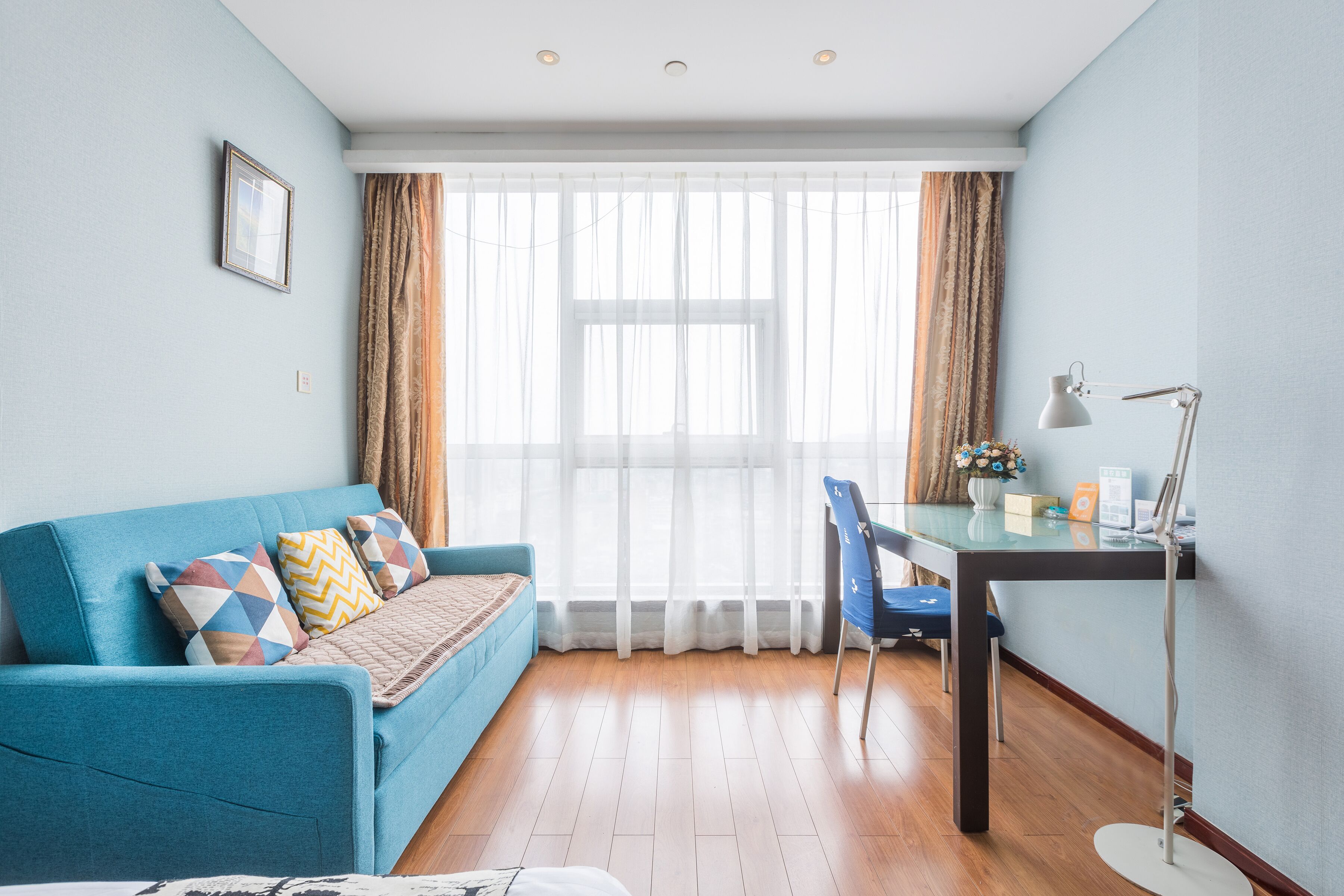 Uma sala de estar moderna com um sofá azul, uma mesa de vidro e uma cadeira.