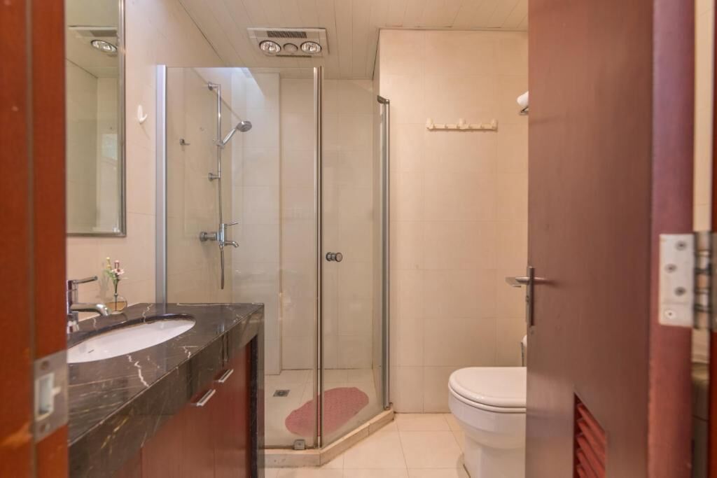 Une salle de bain avec une douche à parois de verre, un lavabo doté d’un plan de toilette en marbre et des toilettes.