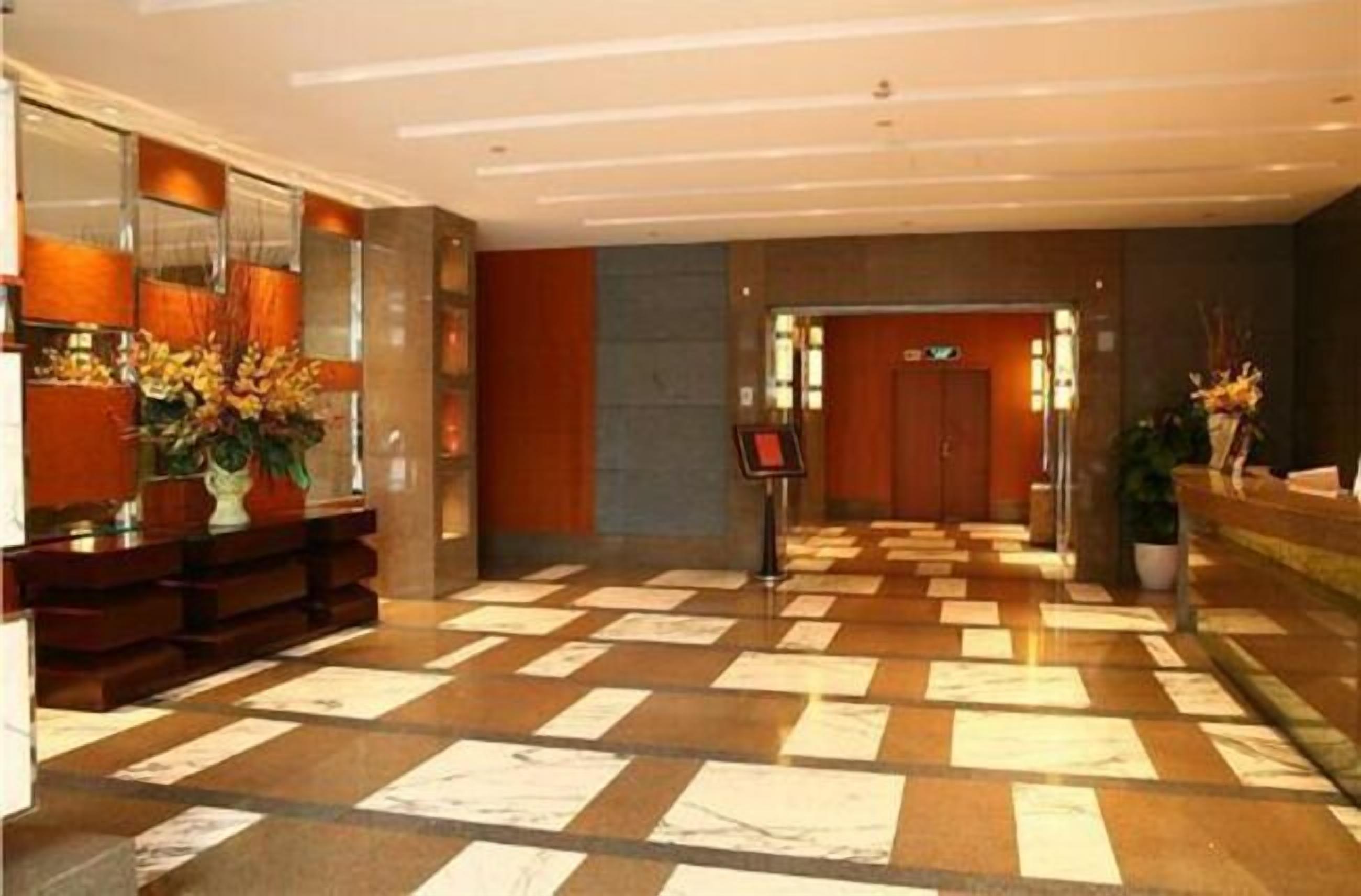 Un hall d’hôtel comprenant un comptoir d’enregistrement, un bureau de réception et un sol carrelé.