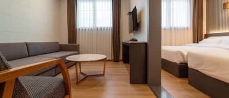 Une chambre d’hôtel moderne équipée d’un canapé, d’une petite table ronde, d’un lit et d’un téléviseur.