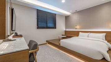 Une chambre d’hôtel moderne avec un grand lit, un bureau et une petite table.