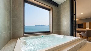 Ein modernes Badezimmer mit einer großen Badewanne, Meerblick durch ein Fenster und einem minimalistischen Design.