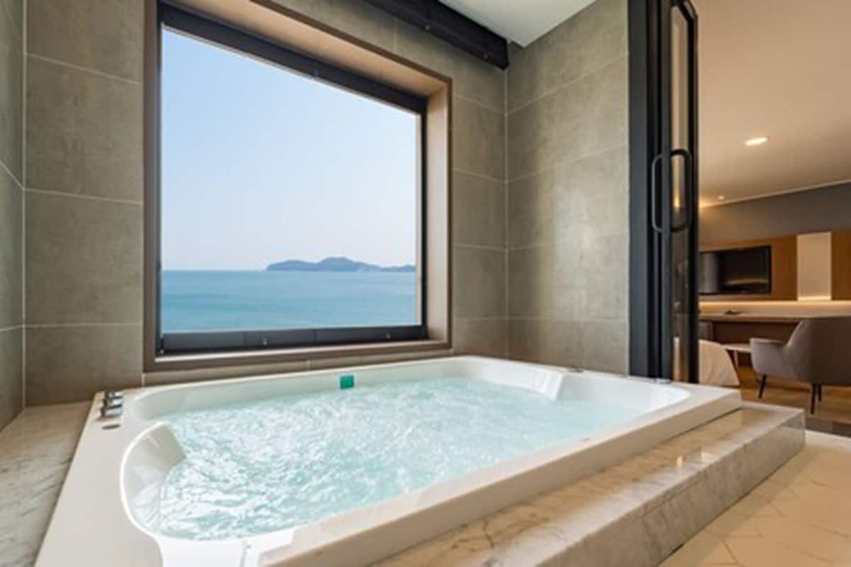 Un baño moderno con una bañera grande, vistas al mar a través de una ventana y un diseño minimalista.