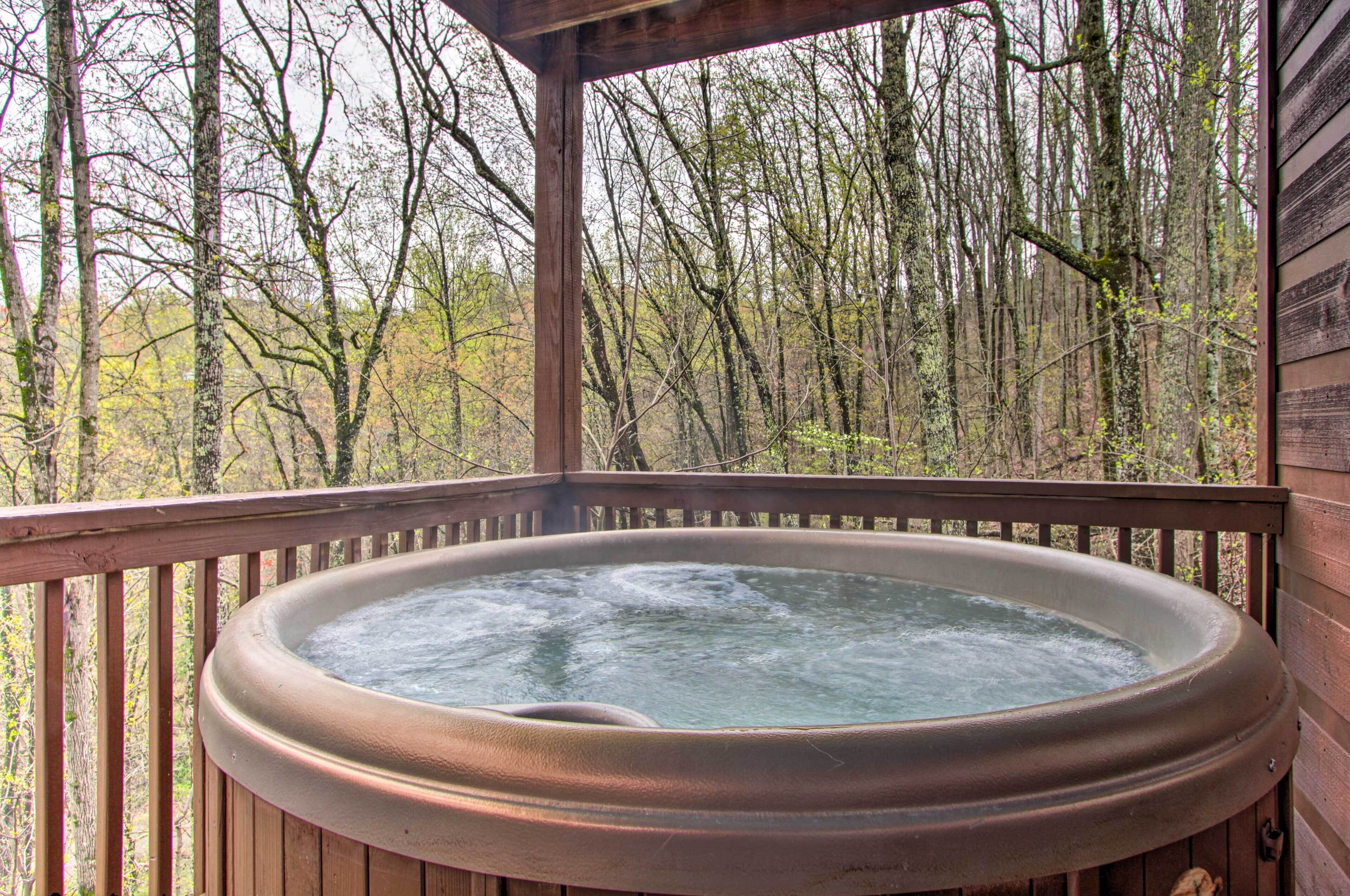 Un jacuzzi en una terraza de madera con vista al bosque.