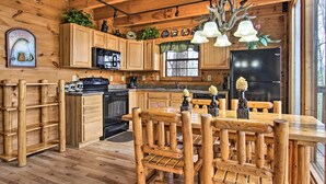 A wooden cabin kitchen with a central island, wooden cabinets, and a black refrigerator.