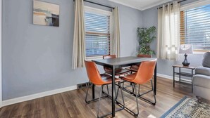 Een eethoek met een tafel, stoelen, een potplant en een lamp.