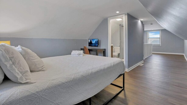 Een slaapkamer met een bed, een bureau, een televisie en uitzicht op het buiten.