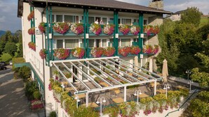 Un hotel con balcón, zona de estar al aire libre y jardineras con flores.