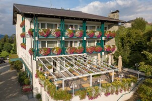 Un hotel con balcón, zona de estar al aire libre y jardineras con flores.