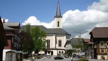 Une église dotée d’un clocher imposant et d’une horloge, entourée de bâtiments et surplombant un ciel dégagé.