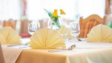 Una mesa vestida con manteles amarillos, un florero con flores amarillas y vasos transparentes.