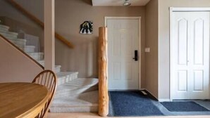 Eine Treppe führt zu einer Tür, ein Holztisch und eine blaue Matte am Eingang.