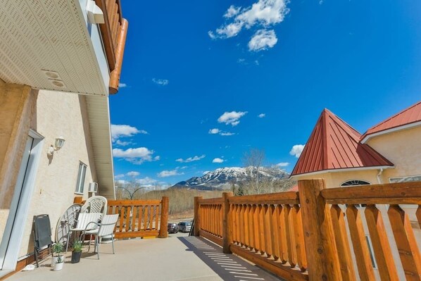 A patio with outdoor furniture, a wooden fence, and a mountain view in the background.
