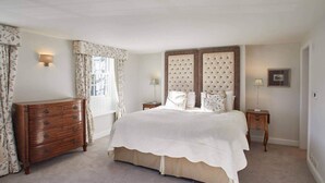 A bedroom with a large bed, a wooden dresser, and a nightstand.
