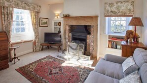A cozy living room with a fireplace, a sofa, a television, and a bookshelf.