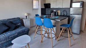 A compact living space with a kitchenette, a sofa with patterned cushions, a small dining table, and blue chairs. - BANYULS-SUR-MER, A/C T2, terrace, parking, near cove (Banyuls-sur-Mer)