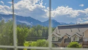 A residential area with houses, a mountain range, and a clear sky. - Spacious Townhouse / Loft Access / Mountain Views (Fernie)