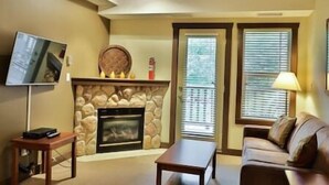 A living room with a fireplace, a television, a sofa, and a table.